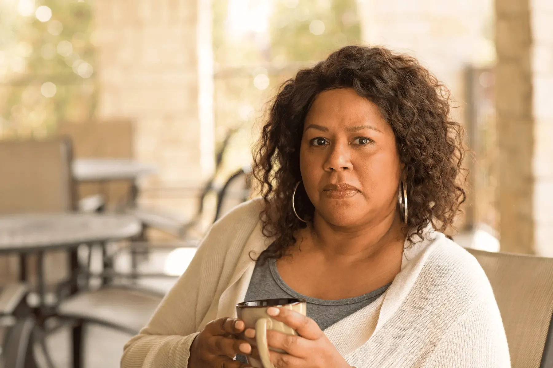 Woman holding cup and sitting thoughtfully