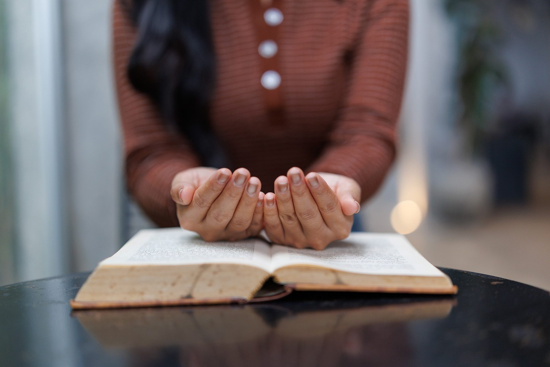 woman-praying-with-open-hands-over-holy-book-on-ta-2025-10-08-12-28-48-utc